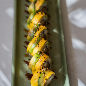 Tempura de camarón, pepino, queso crema, mango y aguacate en rebanadas, salsa unagi y ajonjolí.